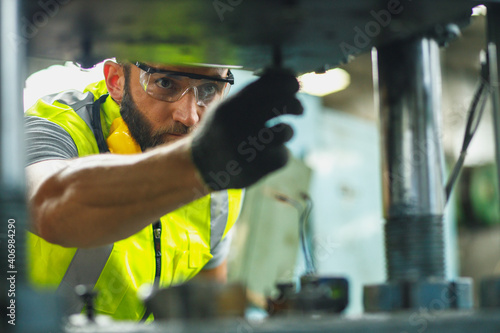 Close up hand industrial industrial plant with a tablet in hand, Engineer looking of working at industrial machinery setup in factory.