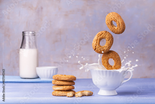 on the lavender blue table, breakfast food, wholemeal biscuits, fall into the cup of milk generating a splash