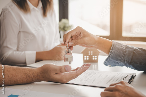 Close up hand of home,apartment agent or realtor was holding the key to the new landlord,tenant or rental.After the banker has approved and signed the purchase agreement successfully.Property concept.