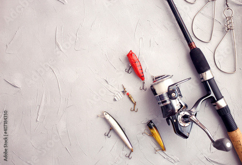 Fishing equipment composition. Rod spinning, wobblers on a gray background. Fishing concept for predatory fish. Flat lay, top view, copy space