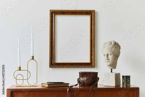 Stylish composition of artist workspace room with design retro teak commode, mock up poster frame, book, decoration and elegant accessories. Template.