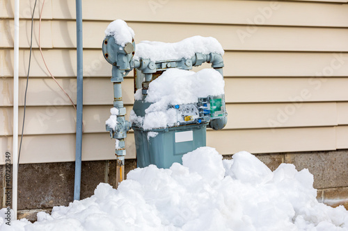 Natural gas meter covered in snow during winter. Concept of energy conservation, residential heating costs and natural gas production