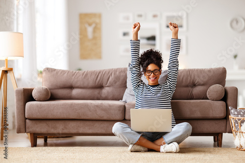 Glad woman celebrating good news while working on laptop at home