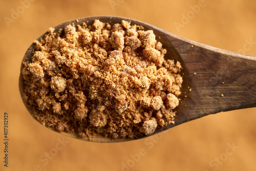 Rapadura or panela - healthy sweetener made by evaporating sugercane juice, on a wooden spoon, closeup