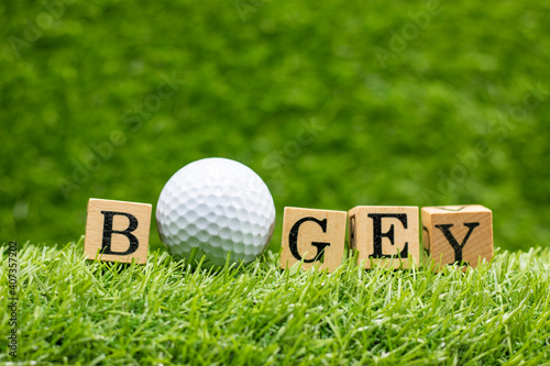 Golf bogey with golf ball and word is on green grass background. in golf, the act of getting the ball into the hole in one shot more than par the expected number for that hole.