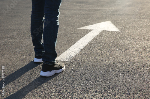 Man going along road with arrow marking, closeup