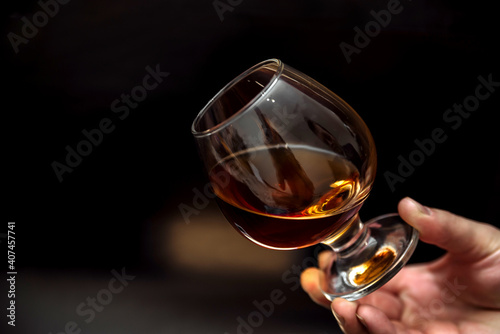 glass of alcoholic drink, hold cognac in hands on a dark background