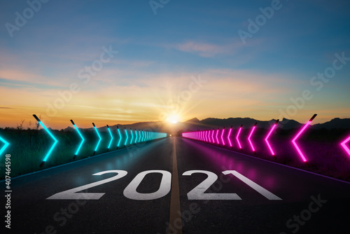 New year 2021 or start straight concept.word 2021 written on the road and neon light of asphalt road at sunset.Concept of planning and challenge or career path,business strategy,opportunity and change