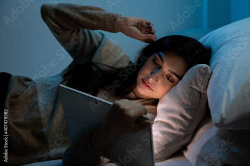 Caucasian women are using the tablet computer on the bed before she sleeping at night, Mobile addict concept, Blue light harmful to the eyes.