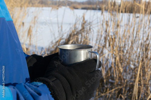 A man in sportswear holds a mug of hot beverage. Concept of winter outdoor recreation. Copy space. Horizontal orientation.