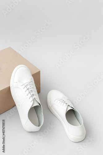 White sneakers and beige box on gray background.