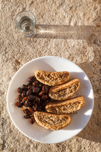 Cretan rusks, olives and tsikoudia (raki), a delicious snack meal as often offered in Crete. All three products are of typical Cretan cuisine.