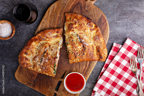 Traditional calzone cut in half served with marinara sauce