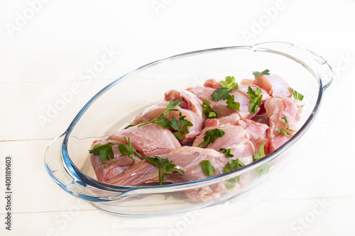 Closeup of the raw chopped chicken meat with cilantro leaf in a glass container