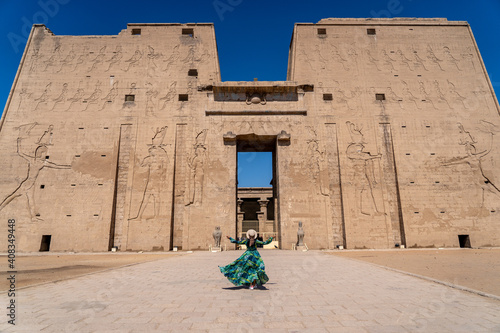 Edfu / Egypt - 02 09 2020: The Temple of Horus at Edfu, A large Ancient Egyptian temple. Women in green dress walking to the gate.