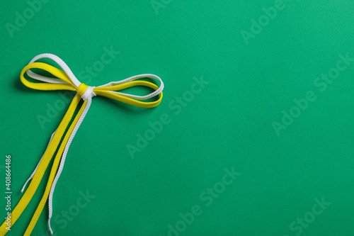 Shoelaces on green background, top view. Space for text