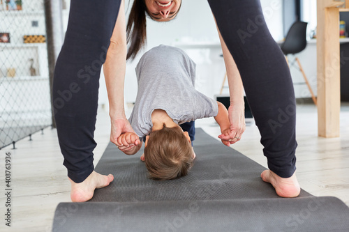 Mother helps child do somersaults at home