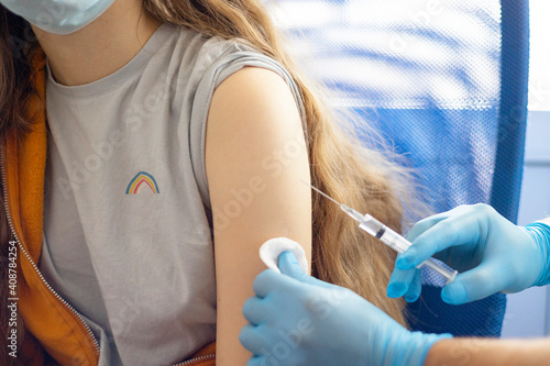 a doctor in gloves vaccinates a teenage girl