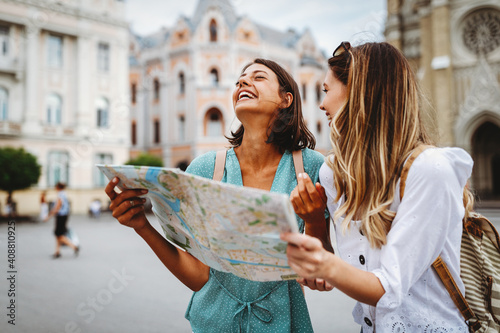 Fun, friends, travel and tourism concept. Beautiful girls looking for direction in the city