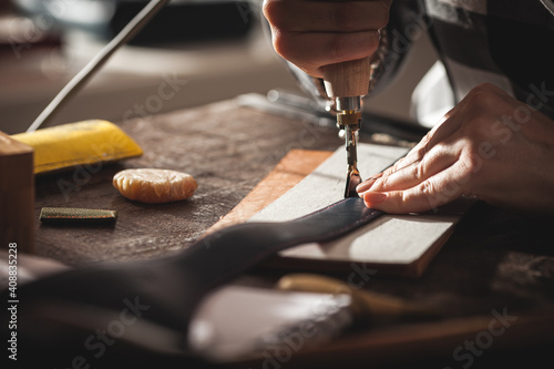 Leather handbag craftsman at work in a vintage workshop. Small business concept