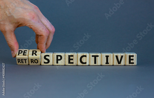 Perspective or retrospective symbol. Businessman hand turns cubes and changes word 'retrospective' to 'perspective'. Beautiful orange background. Business and perspective concept. Copy space.