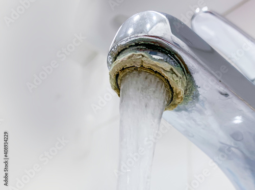 Ein unhygienischer Wasserhahn hat starke Kalkablagerungen