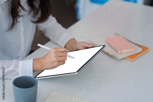 The concept of business woman using tablet in the office with a book beside.