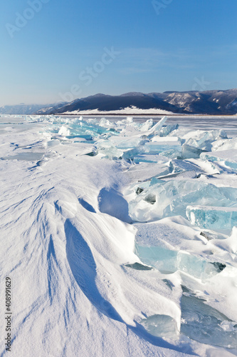 Snow-covered ice hummocks on frozen Lake Baikal on a sunny January day. Beautiful winter landscape. Natural background. Winter travel and ice hikes