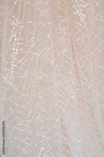 Spider web fabric texture. Pink and peach color. Hanging wedding dress of the bride.