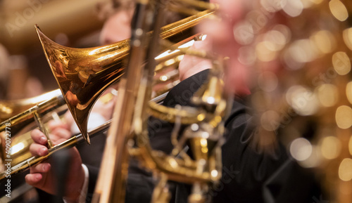 Trumpet professional player with symphony orchestra performing in concert on background.