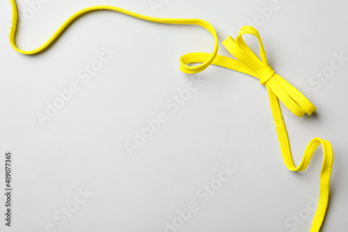 Yellow shoelace on light background, top view. Space for text