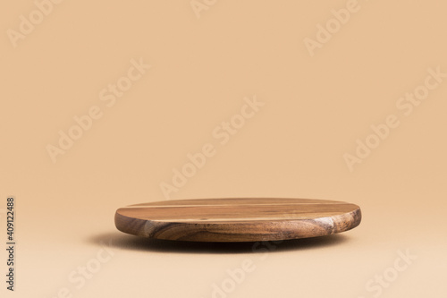 Round wooden flying podium for food, products or cosmetics against bright brown background.