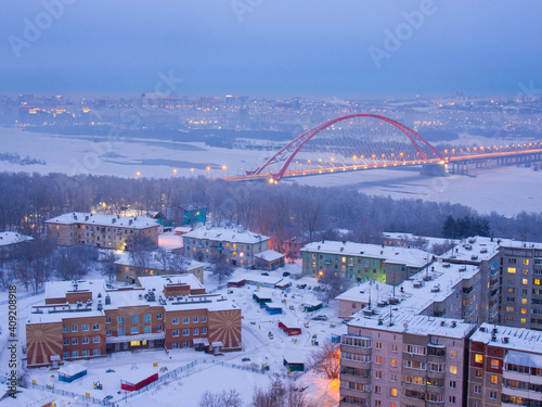 Microdistrict Bugrinskaya grove in Novosibirsk and Bugrinsky bridge across the Ob river in the distance. Orange arch of the bridge over the Ob river