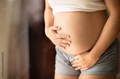 Pregnant woman holding her belly needing to pee with a week bladder. Constipation and bladder prenatal.