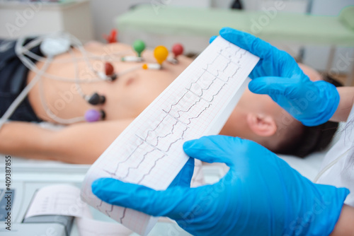 Heart cardiogram in the hands of a doctor close-up. Cardiologist is studying the testimony of an electrocardiograph.