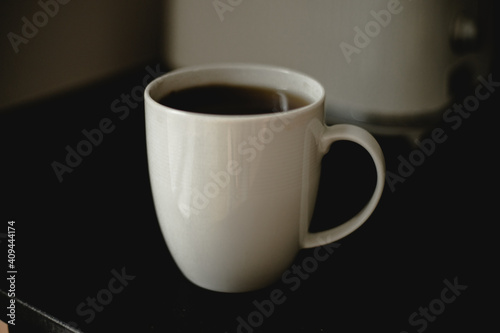 kawa, herbata w białym kubku, filiżance, czarny blat, poranek, biało kubek na czarnym blacie