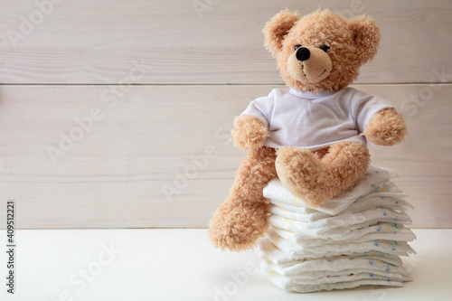 Baby diapers stack and teddy on white color floor