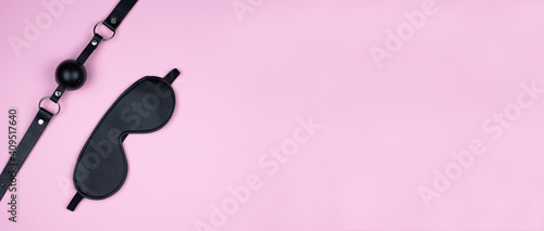 A variety of sex toys (eye mask, harness, gag in the mouth) are presented on a pink background. The image is suitable for advertising and promoting a sex shop. Banner