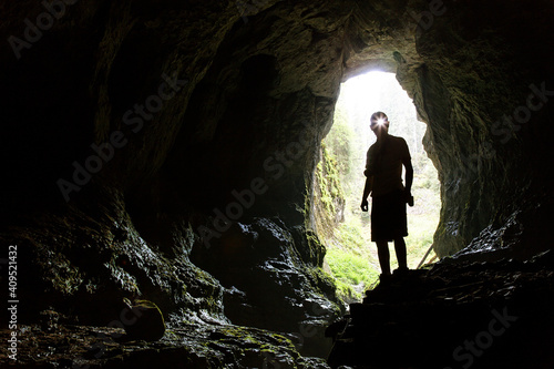Tourist in the Occidental Carpathians, Radesei Cave, Romania. Entrance to the cave, the silhouette of a man against the sky, a huge hole in the rock, see from the cave