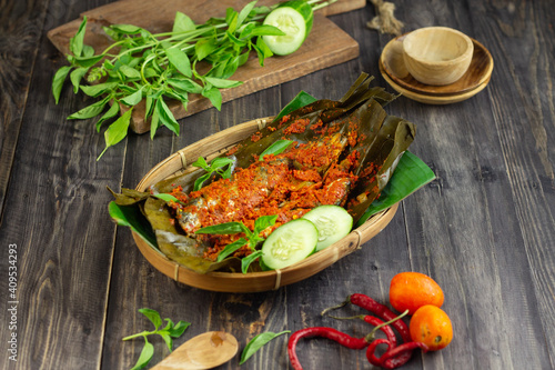 Pepes Ikan Layang or Pais Ikan or Steamed mackerel fish, typically Indonesian traditional food made from fish, spices, wrapped with banana leaves and steamed. Dark Wooden background. 