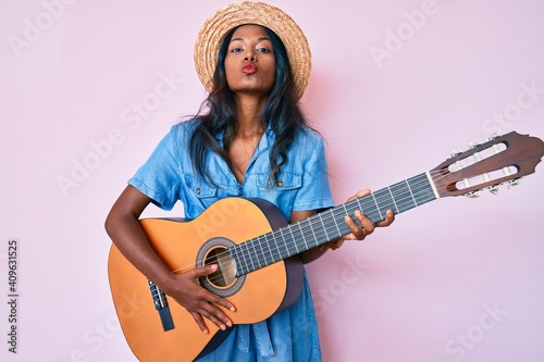 Young indian girl playing classical guitar looking at the camera blowing a kiss being lovely and sexy. love expression.