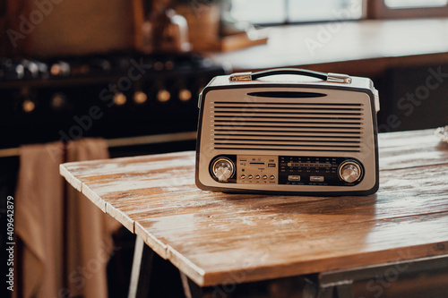 an old vintage radio receiver sits on a wooden table. stylish old kitchen morning in the village and daylight from the window. copy space