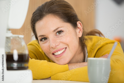 portrait of woman leaning on worktop by coffee machine