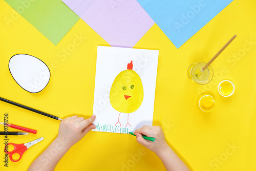 DIY and kids creativity. Step by step instruction: Create an Easter card with chicken. Childrens handmade Easter craft. Top view Step 9. draw grass chicken with a green felt-tip pen