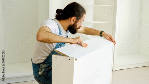 Furniture assembly process. A man is assembling the drawer for the wardrobe.