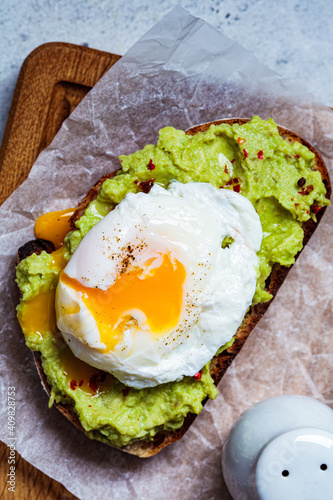 Avocado toast with poached egg on wooden board, top view. Breakfast concept.