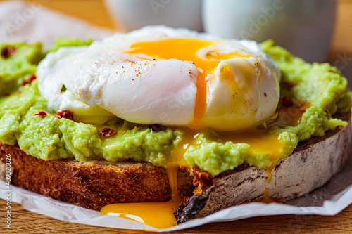 Avocado toast with poached egg on wooden board. Breakfast concept.