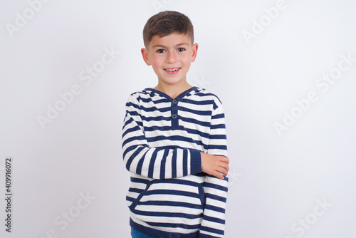 little cute boy kid wearing stripped t-shirt against white wall laughing.