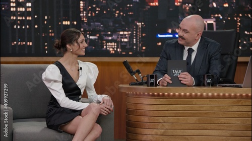 Late-night talk show host having a conversation with celebrity guest in a studio. TV broadcast style show