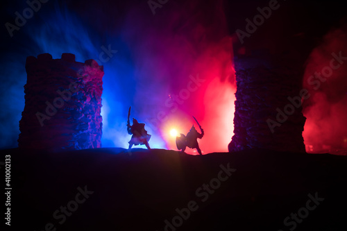 Medieval battle scene. Silhouettes of figures as separate objects, fight between warriors at night. Creative artwork decoration. Foggy background.